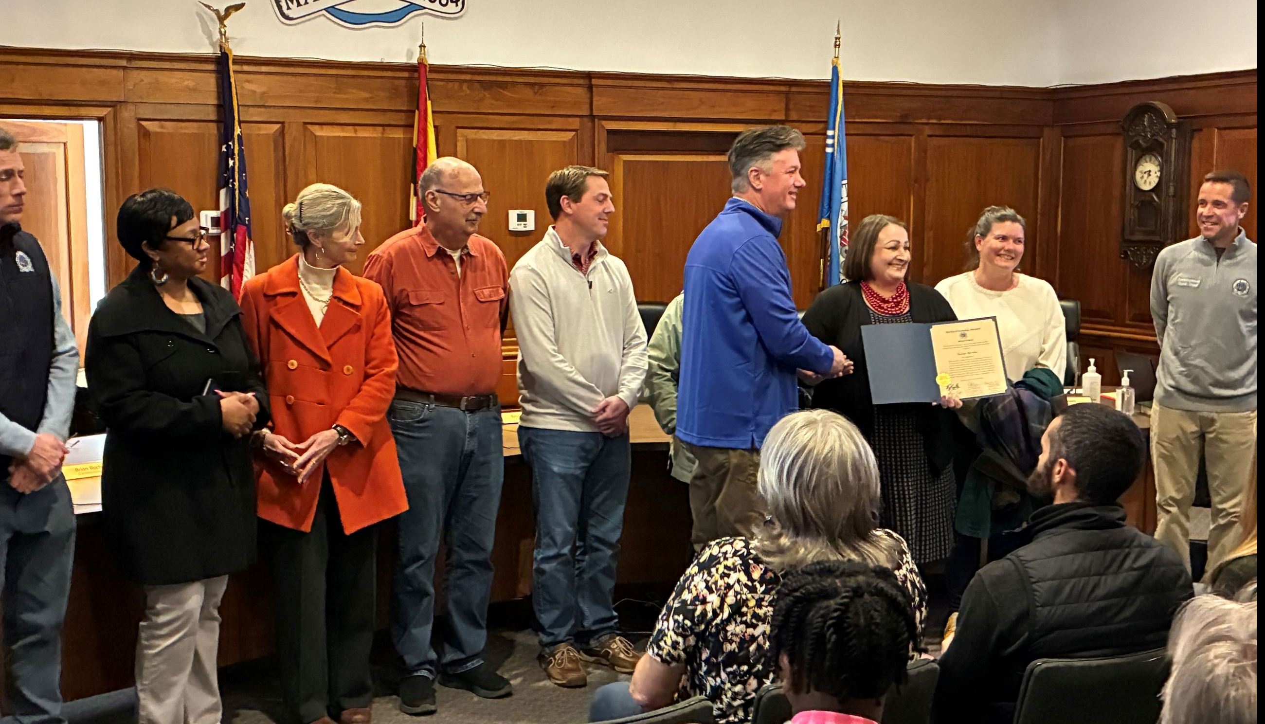Community member and Commissioners standing in the Cambridge Council chamber in front of the dias