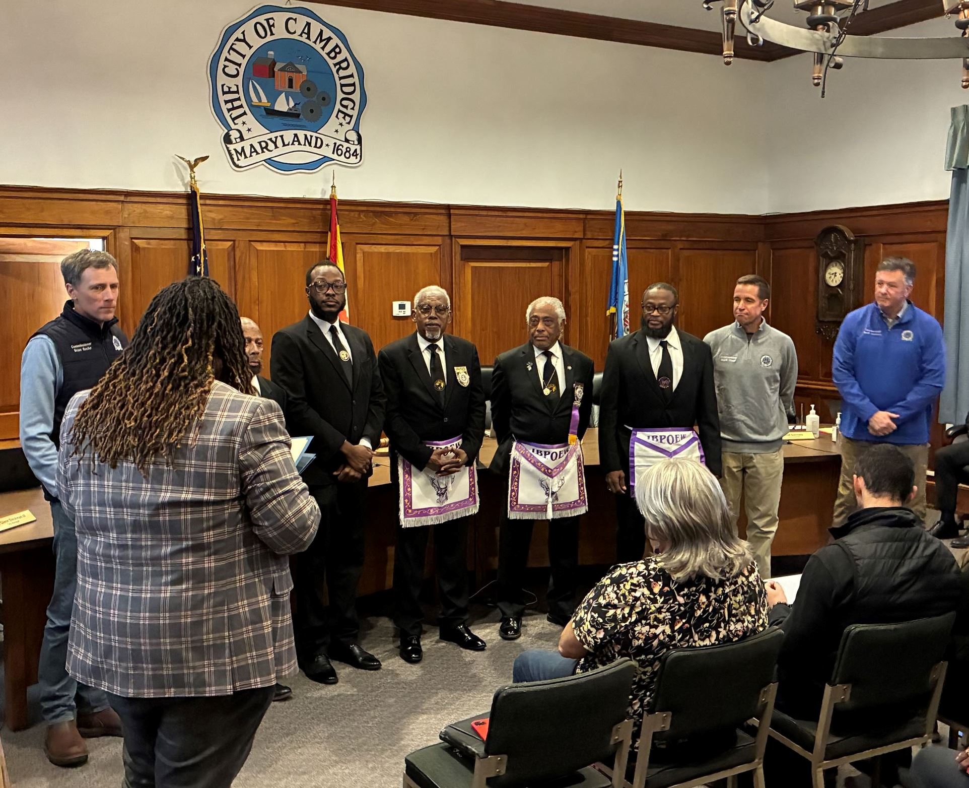 Community member and Commissioners standing in the Cambridge Council chamber in front of the dias