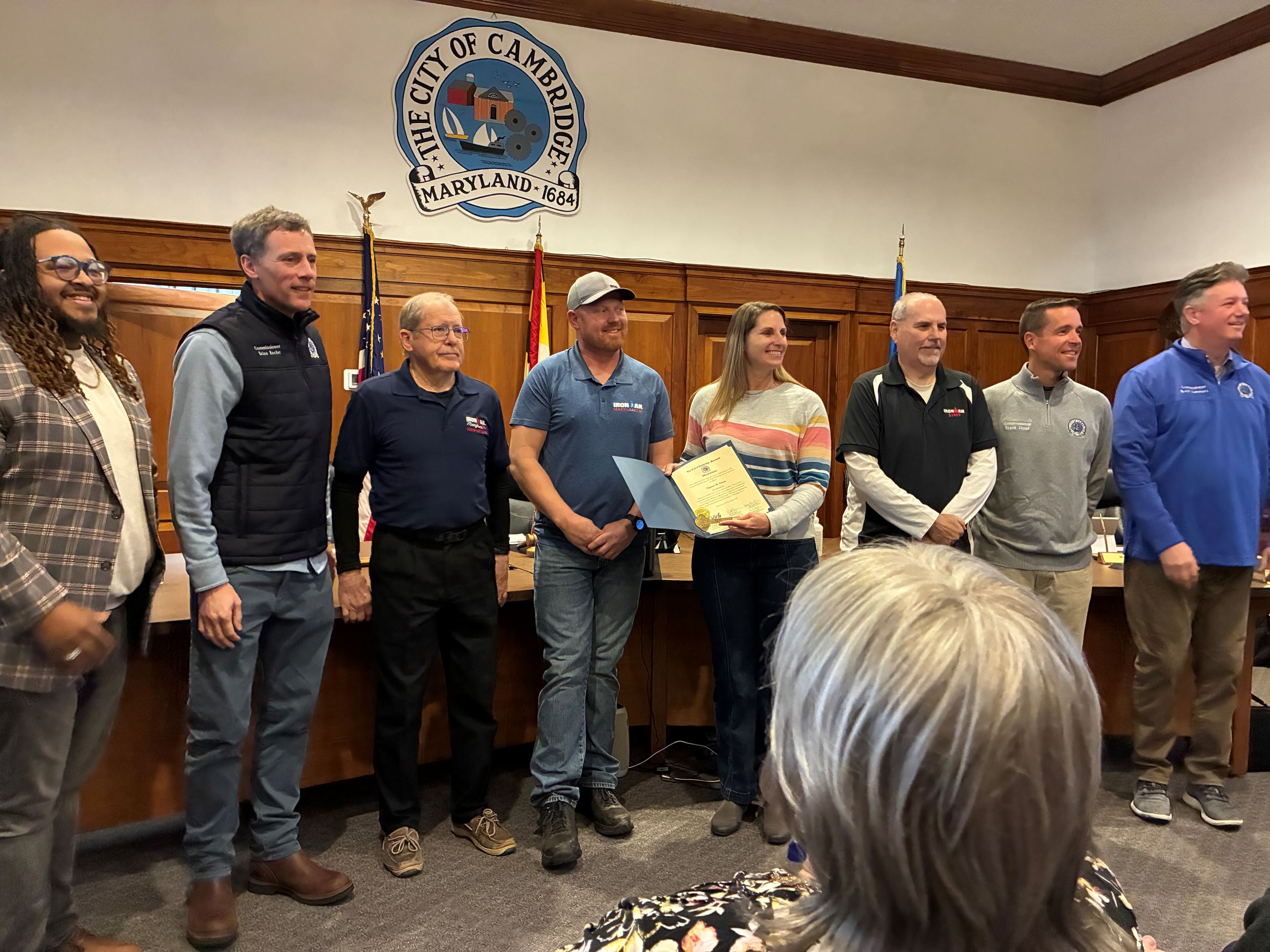 Community member and Commissioners standing in the Cambridge Council chamber in front of the dias